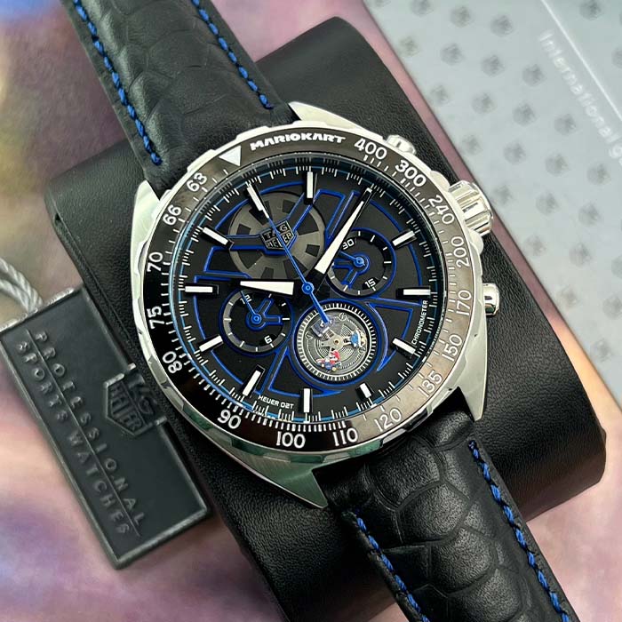 Reloj TAG Heuer Mario Kart Racing con cronógrafo, detalles en azul, correa de cuero negro y maquinaria visible, estilo deportivo de lujo.
