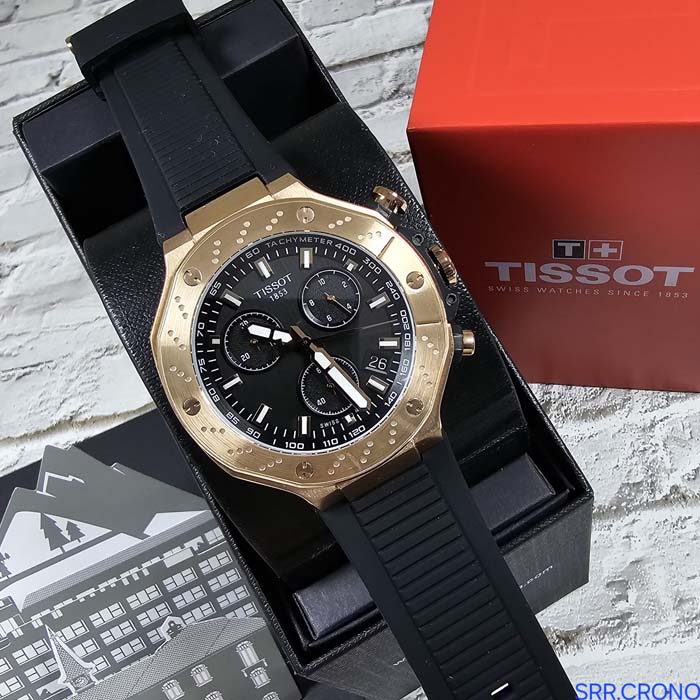 Reloj Tissot deportivo con bisel dorado, cronógrafo y correa negra de silicona, estilo moderno para hombre.