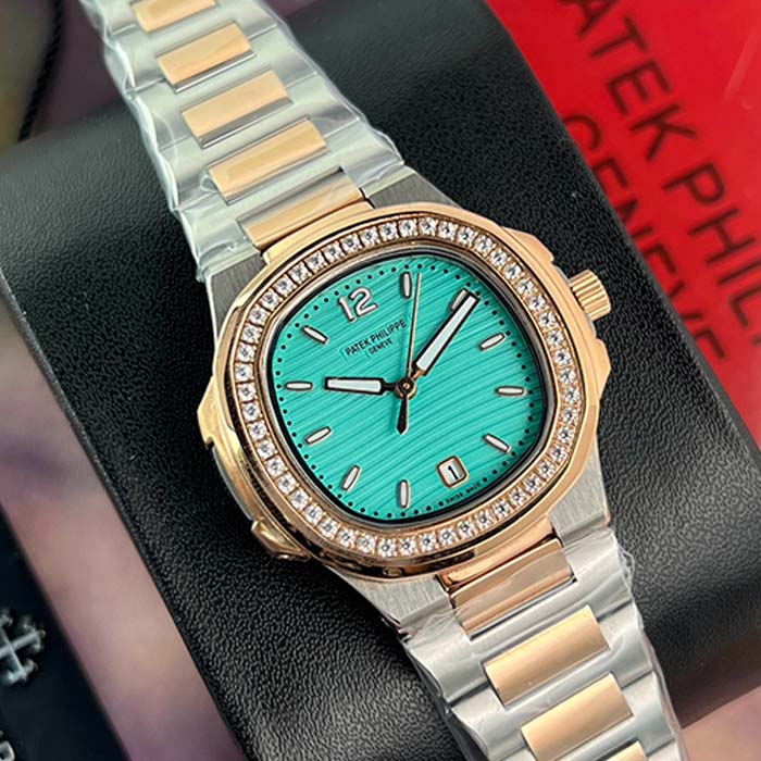 Reloj Patek Philippe Nautilus para mujer con carátula verde agua, bisel adornado con cristales y brazalete bicolor en acero y oro rosado, estilo elegante y moderno.