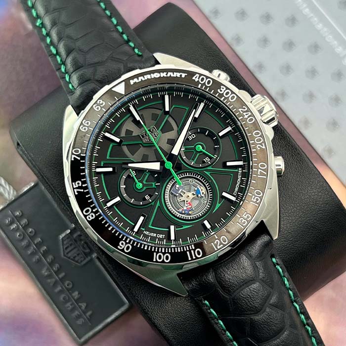 Reloj TAG Heuer Mario Kart Racing con cronógrafo, detalles en verde, maquinaria visible y correa de cuero negro con costura verde.