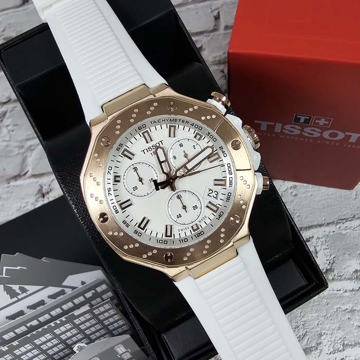 Reloj Tissot deportivo con correa blanca, cronógrafo funcional y bisel dorado, ideal para hombre moderno.