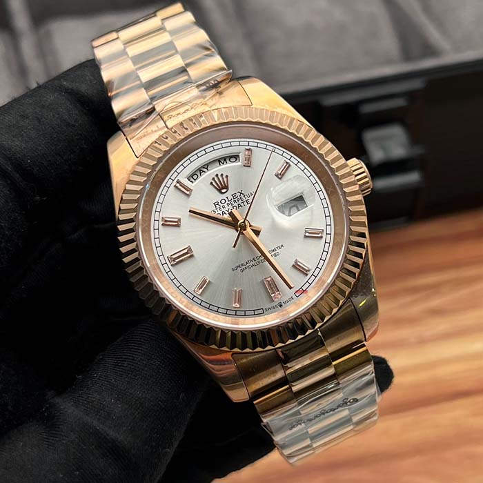 Reloj estilo Rolex Day-Date en oro rosado con esfera plateada y marcadores brillantes, ideal para hombres elegantes en Colombia.