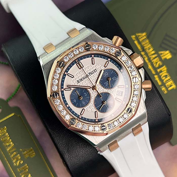 Reloj Audemars Piguet Royal Oak con correa blanca, detalles en oro rosa, subesferas azules y bisel con brillantes, estilo elegante y moderno.