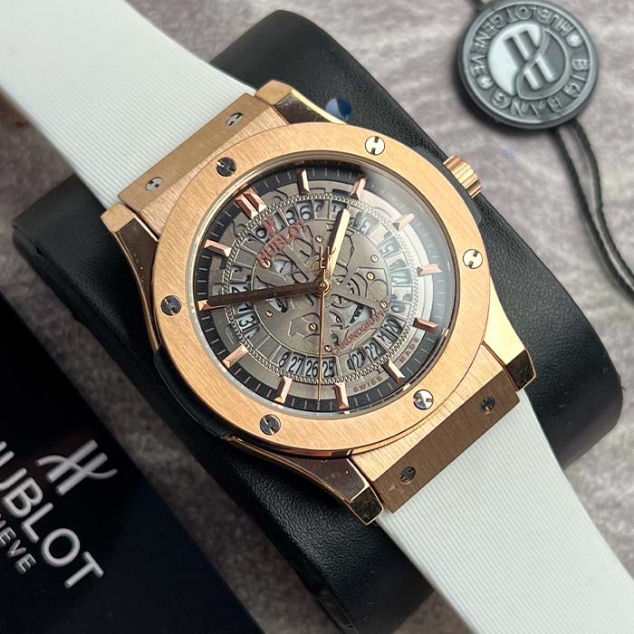 Reloj Hublot con caja dorada, carátula skeleton y correa blanca, diseño elegante para hombres que buscan estilo y presencia.