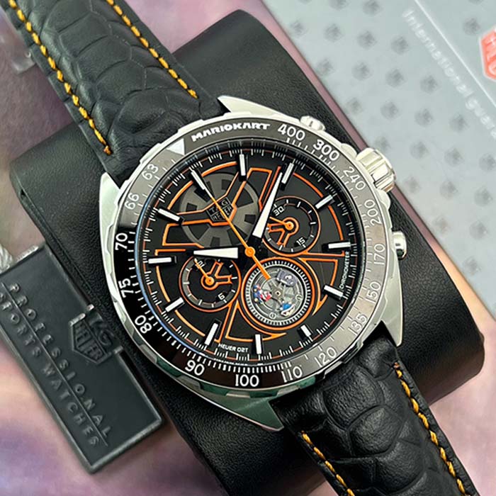 Reloj TAG Heuer Mario Kart edición especial con detalles en naranja, cronógrafo deportivo y correa de cuero negra.