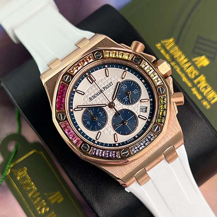 Reloj Audemars Piguet oro rosa con correa blanca y bisel multicolor tipo rainbow, diseño llamativo y elegante para mujeres con estilo.