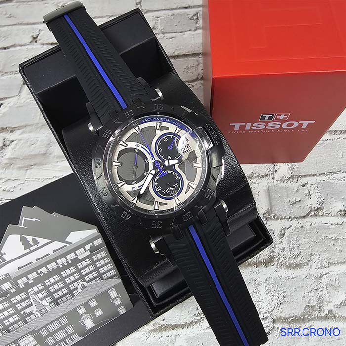 Reloj Tissot T-Race con diseño automovilístico, carátula metálica, correa negra con franja azul y estilo deportivo ideal para uso diario.