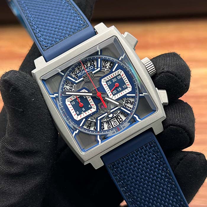 Reloj TAG Heuer Monaco azul con diseño cuadrado, correa texturizada y cronógrafos funcionales, ideal para un look moderno y casual.