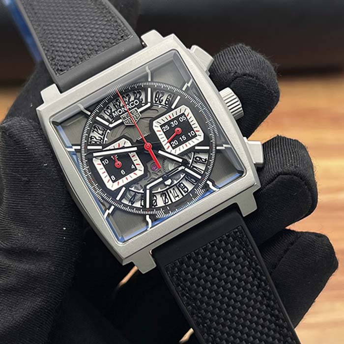 Reloj TAG Heuer Monaco negro con diseño skeleton visible, caja cuadrada y correa texturizada, ideal para un estilo moderno y elegante.