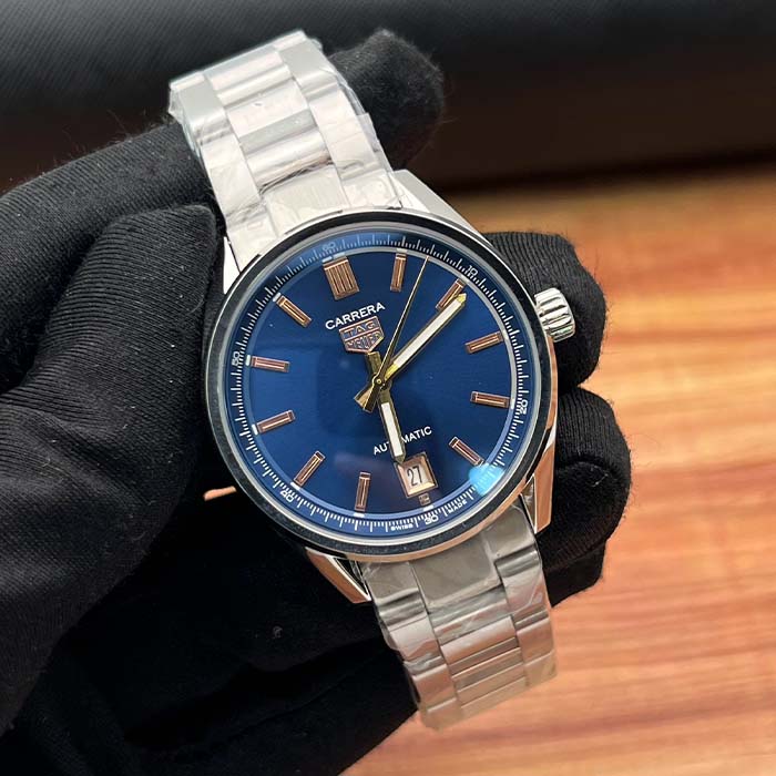 Reloj TAG Heuer Carrera automático con esfera azul, marcadores dorados y correa metálica plateada, estilo clásico y sofisticado.