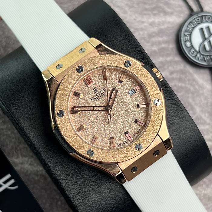 Reloj Hublot color oro rosado con acabado escarchado brillante y correa blanca de silicona, ideal para mujer, estilo moderno y llamativo.
